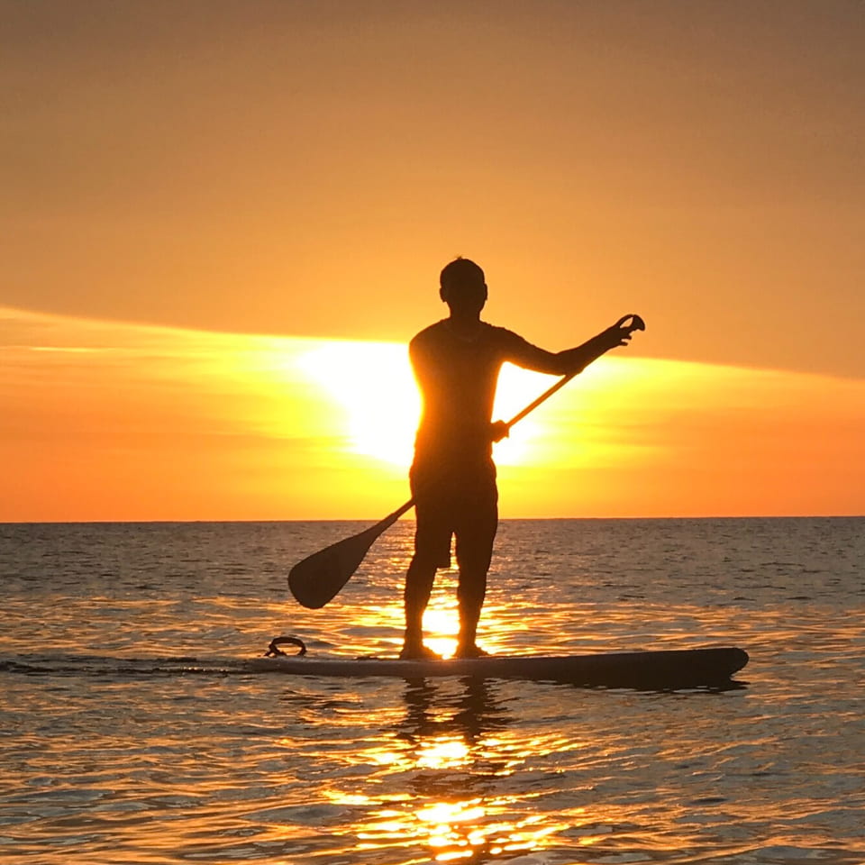 Chico haciendo Paddle Surf al atardecer
