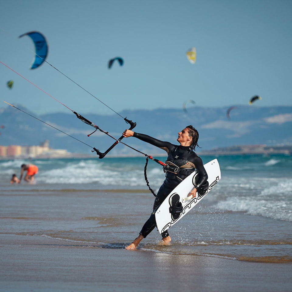 Kitesurfer saliendo del mar en Tarifa con la cometa y la tabla en la mano