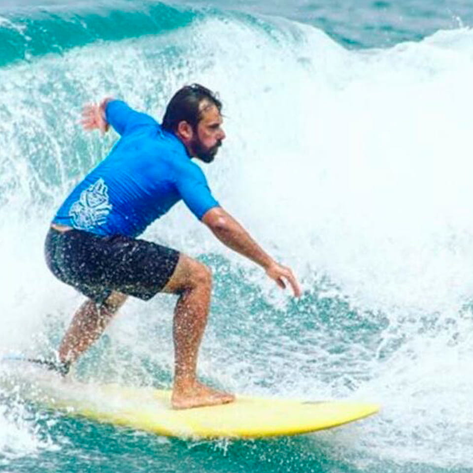 Surfero bajando una ola sobre tabla amarilla