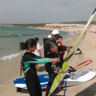 Monitor de windsurf dando clases a niños en el mar