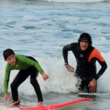 Profesor de surf enseñando a un niño a pillar espumones
